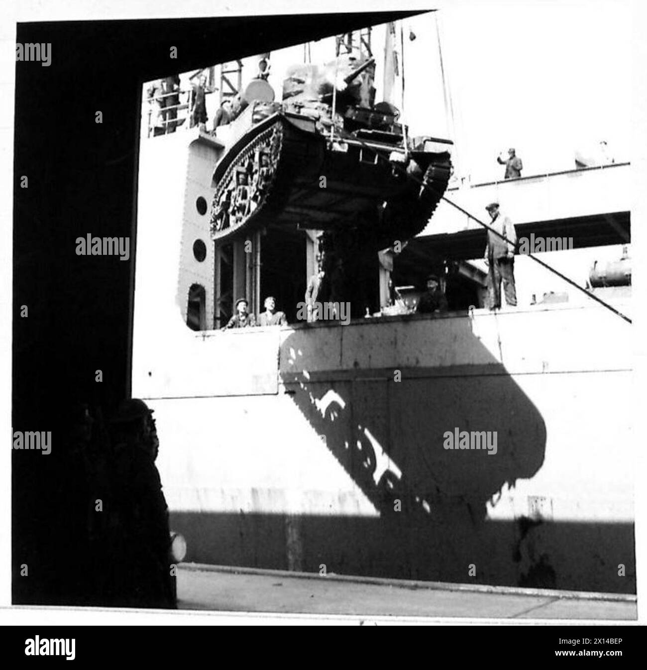 MEHR AMERIKANISCHE AUSRÜSTUNG KOMMT AN – „langsam macht es!“ Hafenarbeiter beobachten das Absenken eines amerikanischen Panzers mit großem Interesse der britischen Armee Stockfoto