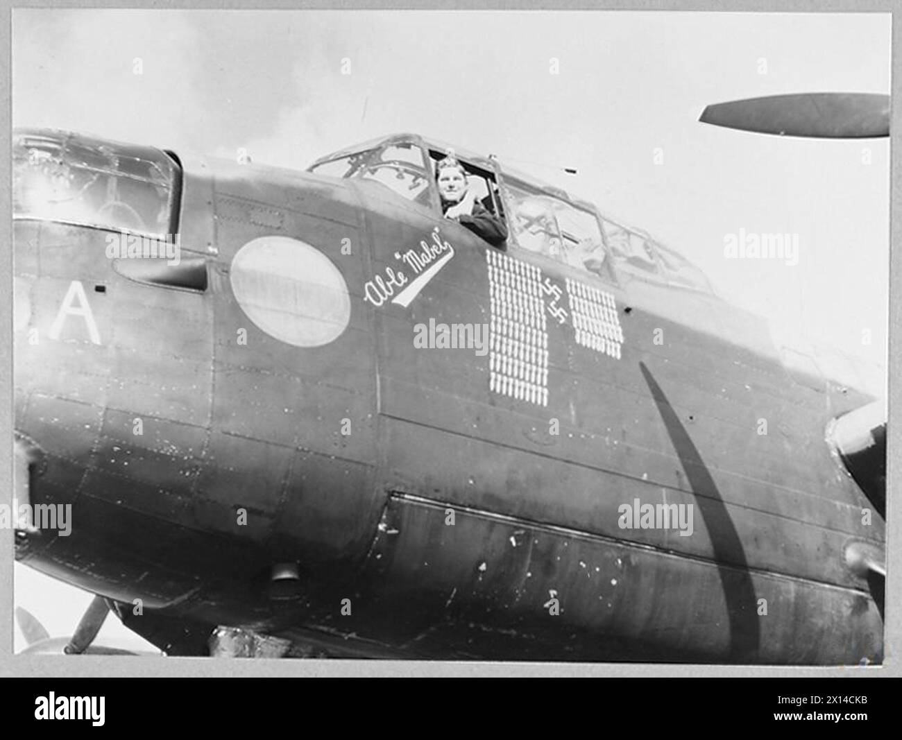 R.A.F. LANCASTER SCHLIESST 121 OPS AB - Picture (ausgestellt 1945) Shows - Flight Lieutenant J.D. Playford, 23 Jahre alt von 55 Watson Avenue, Tornoto, Piloten der Lancaster 'Abable Mabel', die 121 operative Flüge mit dem R.A.F. Bomber Command absolviert hat. Ihre Geschütze haben zwei feindliche Kämpfer abgeschossen, wie die Hakenkreuze unter ihrem Bombenbaum die Royal Air Force zeigen Stockfoto