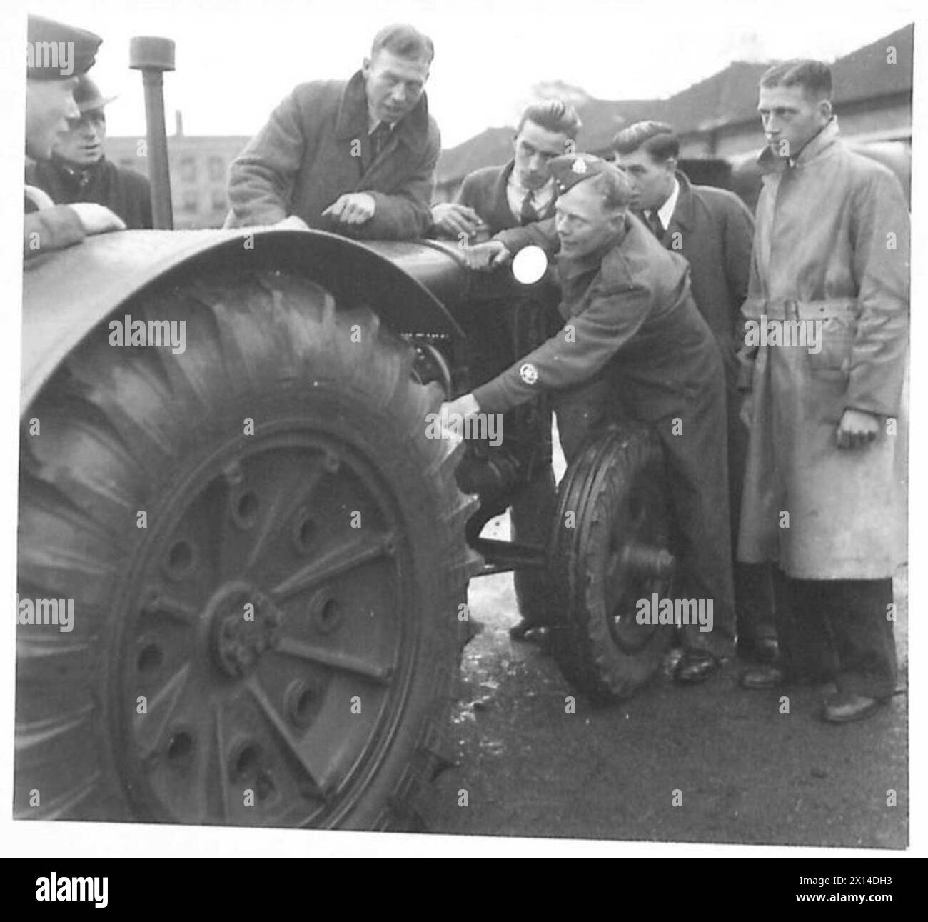 Soldaten unterstützen Junglandwirte, während ein Senior NCO Vorträge über die Wartung von Traktoren hält Stockfoto