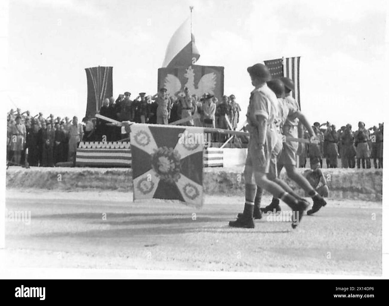 Truppen des 2. Polnischen Korps marschieren an einer Bühne vorbei, die einen neuen Regimentsstandard zeigt. Generalmajor Frederick Beaumont-Nesbitt, Verbindungsoffizier der Alliierten des Nahost-Kommandos, und General Władysław anders, C-in-C des 2. Polnischen Korps, grüßen während einer Parade in Gaza zum 25. Jahrestag des polnischen Unabhängigkeitstages 1942-1943. Stockfoto Truppen des 2. Polnischen Korps marschieren an einer Bühne vorbei, die einen neuen Regimentsstandard zeigt. Generalmajor Frederick Beaumont-Nesbitt, Verbindungsoffizier der Alliierten des Nahost-Kommandos, und General Władysław anders, C-in-C des 2. Polnischen Korps, grüßen während einer Parade in Gaza zum 25. Jahrestag des polnischen Unabhängigkeitstages 1942-1943. Stockfoto