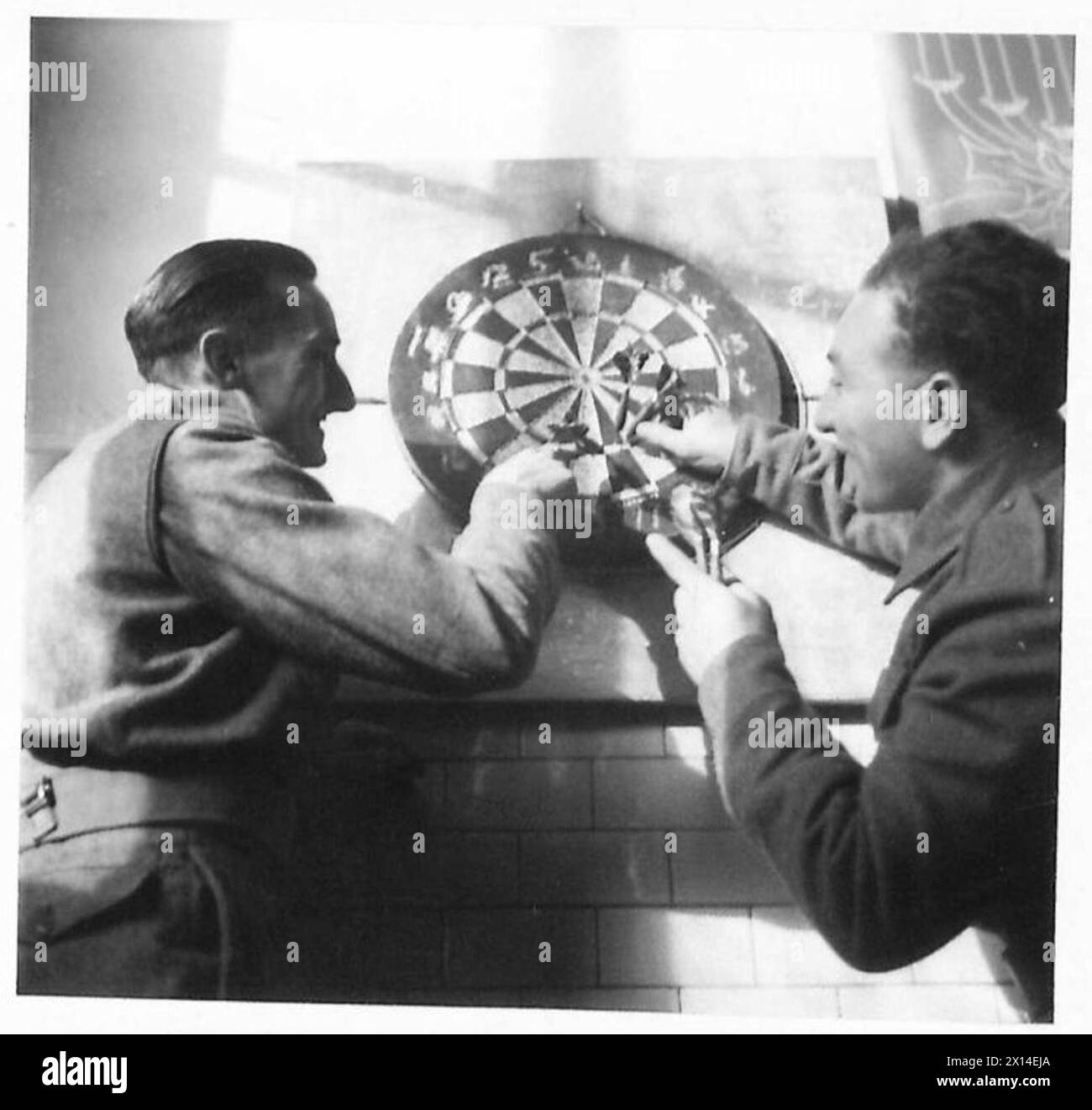 WEIHNACHTEN MIT DEM B.L.A. 1944 - "ist es - oder "nicht?". Links, Gnr. E.W. Hinton (Croydon) und Pte. J.H. Cohen (Leeds) stimmen überein, sich im Dart Board British Army, 21st Army Group, zu unterscheiden Stockfoto