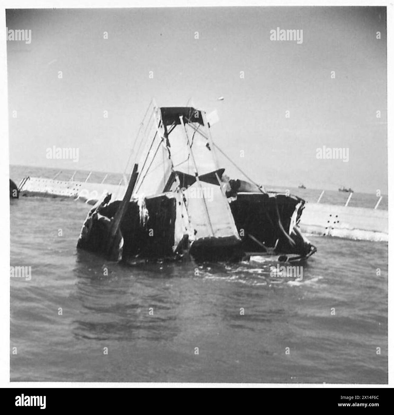 Bau eines schwimmenden Hafens in Arromanches, Normandie, mit Phoenix Caissons und beschädigter Ausrüstung, die von der britischen 21. Armee-Gruppe dokumentiert wurde. Stockfoto