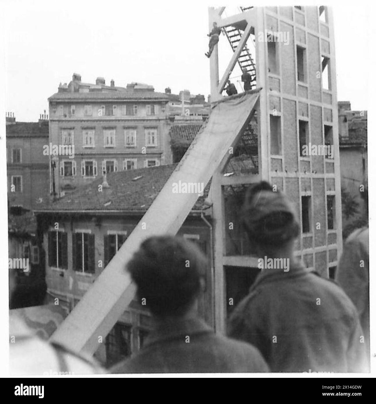 ITALIEN: FEUERWEHRDEMONSTRATION TRIEST - Triester Feuerwehrleute springen aus einer 100 m hohen Höhe. Hohes Gebäude in einen Segelschirm oder eine Fluchtrutsche. Diese Bilder zeigen Feuerwehrmänner, die drei Stockwerke über der Fluchtrutsche der British Army springen Stockfoto