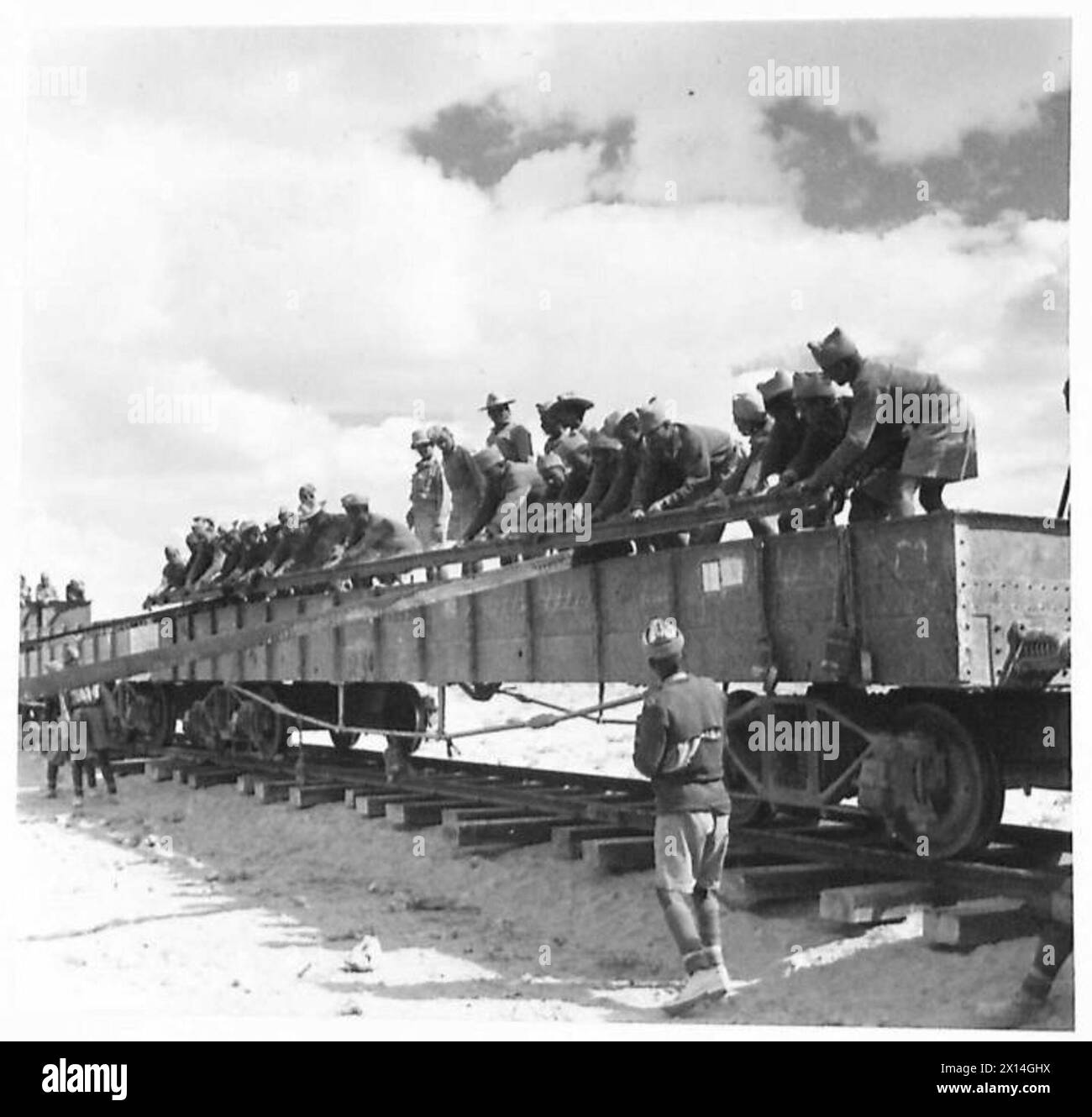 Das indische Labour Corps entlädt Waggons mit Längen auf einer teilweise fertiggestellten Eisenbahnstrecke, wobei die Schienen während des Bauens der British Army sequenziell auf den Boden gelegt wurden. Stockfoto
