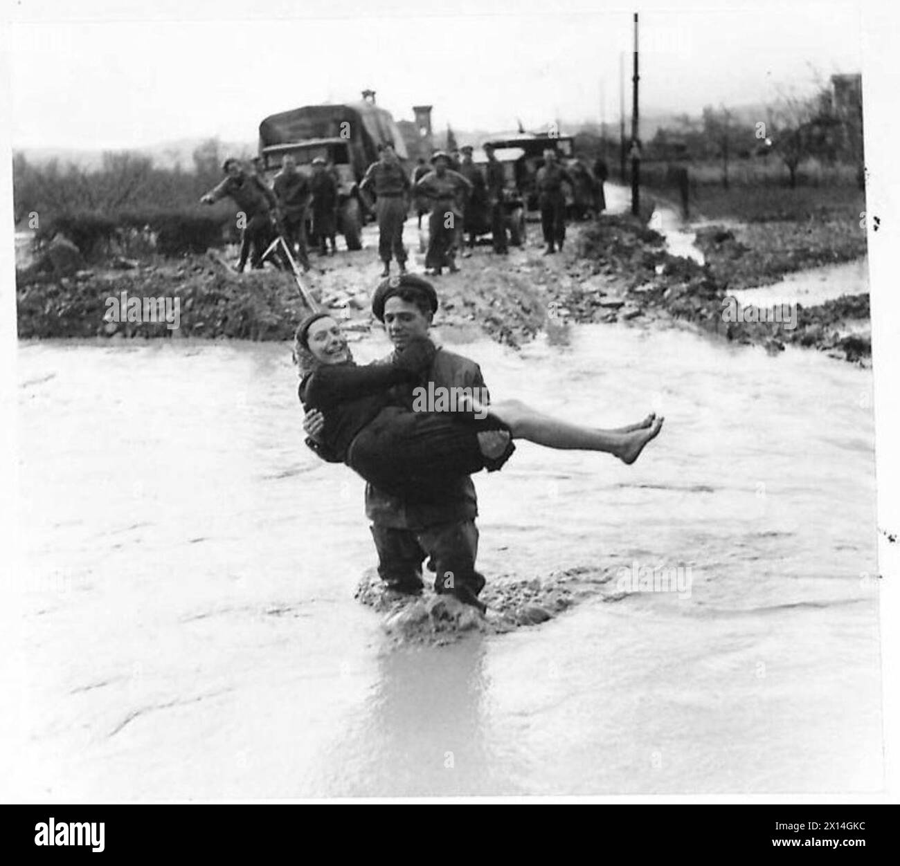 ACHTE ARMEE : SCHLECHTWETTER BEHINDERT OPERATIONEN - SPR. M.W. Jones von 35 Coegnant Road, Saerav, Bridgend, Glamorgan, trug einen italienischen Zivilisten über eine abgespülte britische Armee Stockfoto