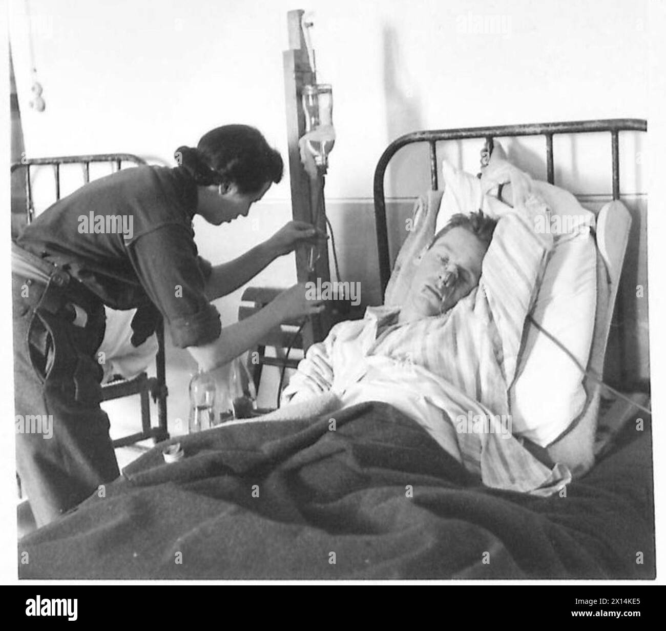 Schwester Gibson, eine Krankenschwester an der Front der britischen 8. Armee in Italien, bereitet eine Salzlösung für Private Fox aus Bridgetown, Halifax, Kanada vor. Stockfoto