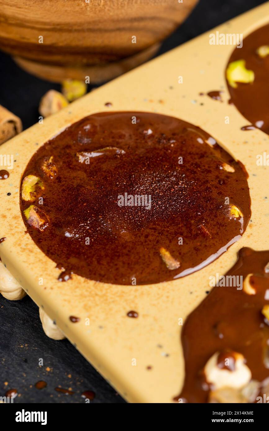 Geschmolzene Milchschokolade mit Nüssen, kochende Schokoladentafeln mit heißer Milchschokolade und Nüssen Stockfoto
