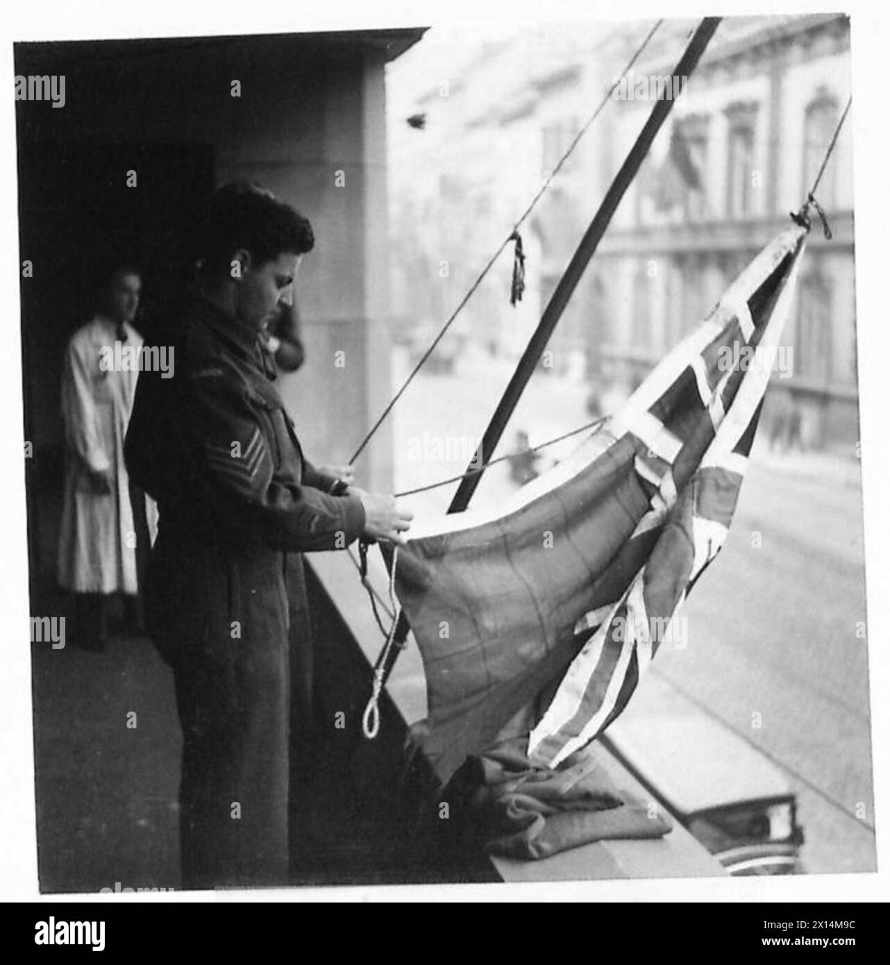 Sergeant M. Jutras von der Royal Canadian Artillery befestigt den Royal Standard an einem Fahnenmast während der Friedensfeiern in Brüssel. Stockfoto