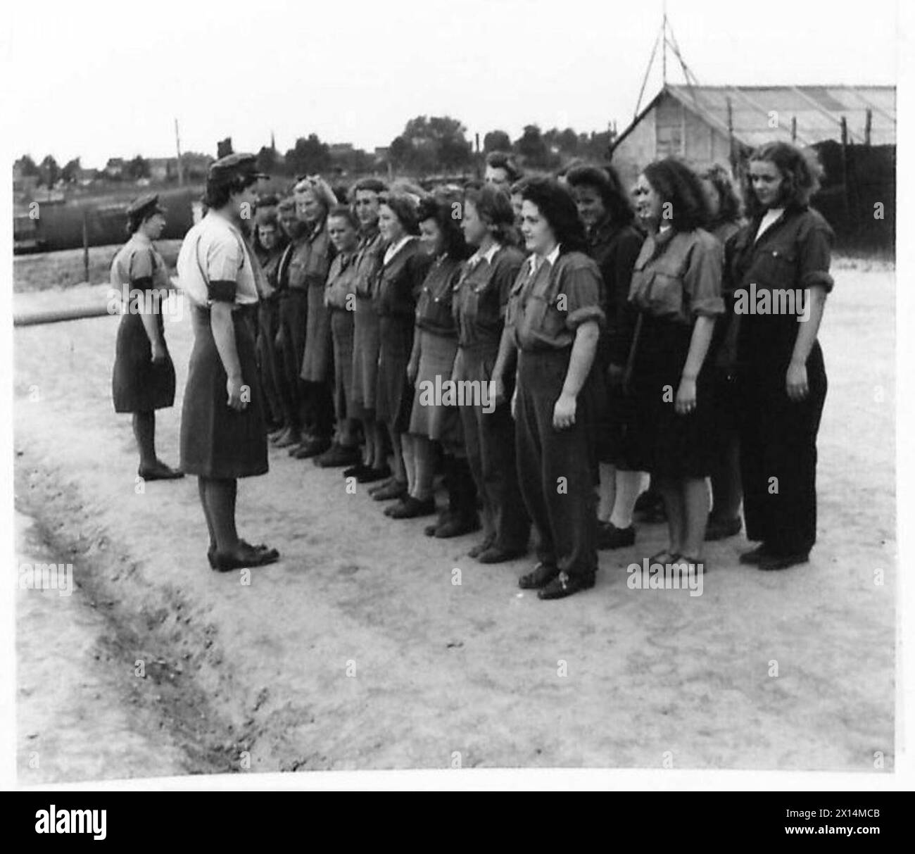 DEUTSCHE S.S., LUFTWAFFE UND ZIVILFRAUENLAGER - L/Corporal E. J. Burck und andere A.T.S., die während der Morgenparade mit einem der Gefangenen sprechen, britische Armee, 21. Armeegruppe Stockfoto