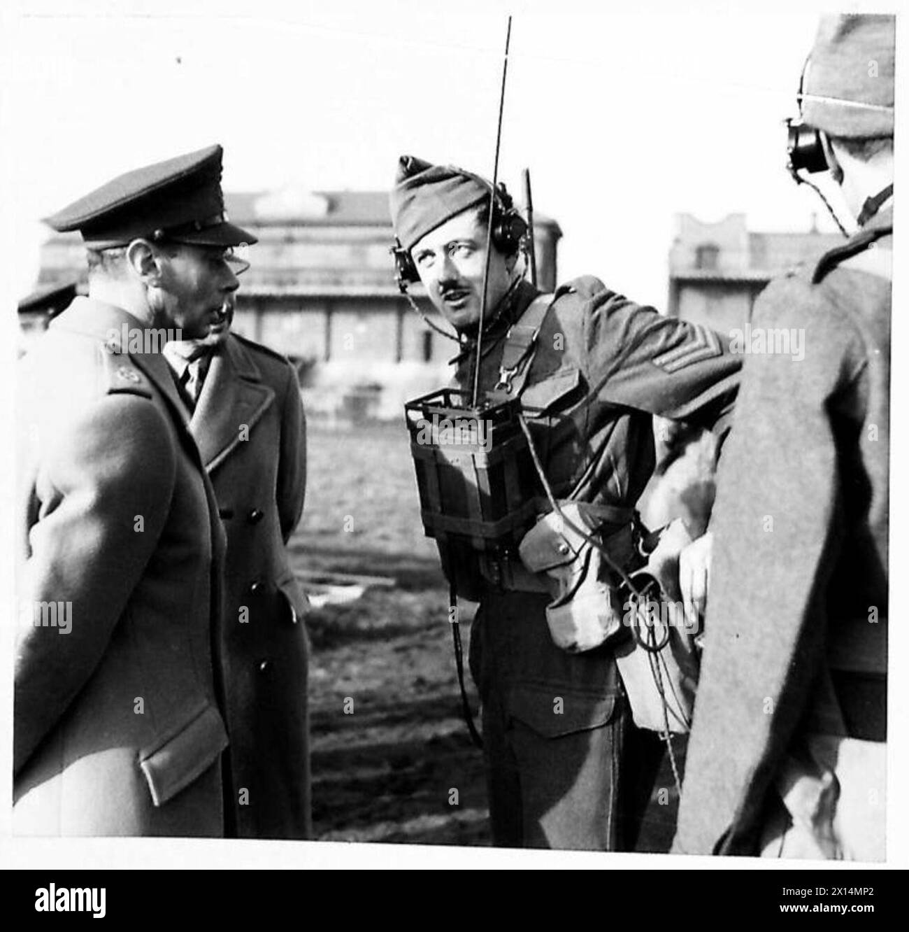 Seine Majestät der König beobachtet einen Feldsignalkorporal der Irish Guards, der während einer Übung auf dem Ayr Race Course ein tragbares Funkgerät demonstriert. Stockfoto
