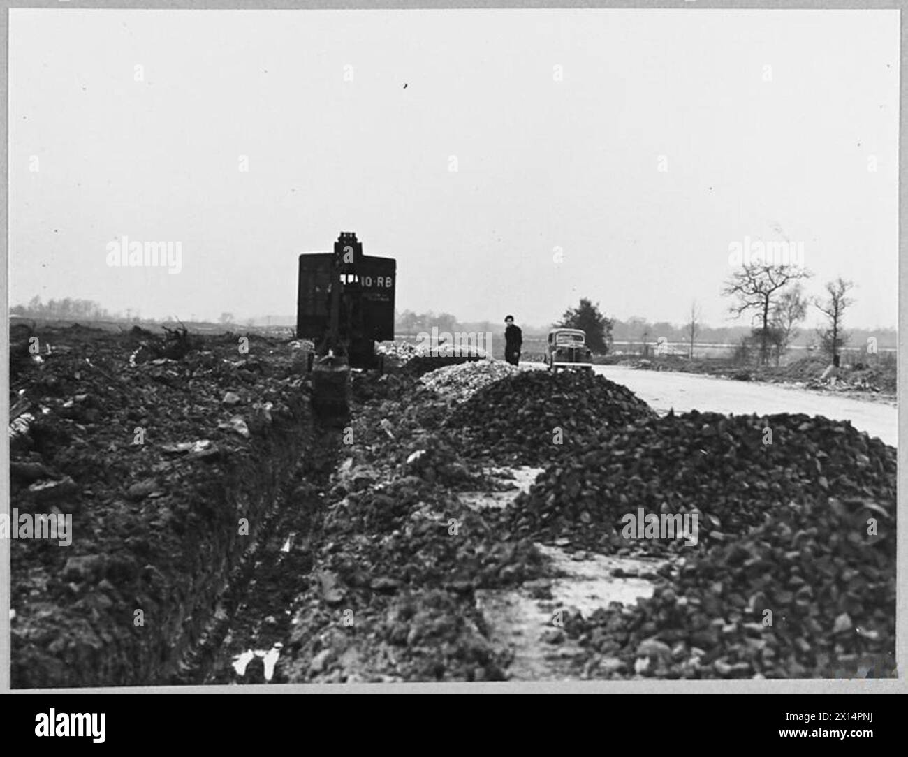 Ruston Bucyrus Model 10 R.B., ausgestattet mit Grabenbauwerkzeugen, arbeitet neben einer Landebahn und gräbt Entwässerungsgräben für den Flugplatzbau während des Zweiten Weltkriegs unter Aufsicht des Ministeriums für Versorgung. Stockfoto