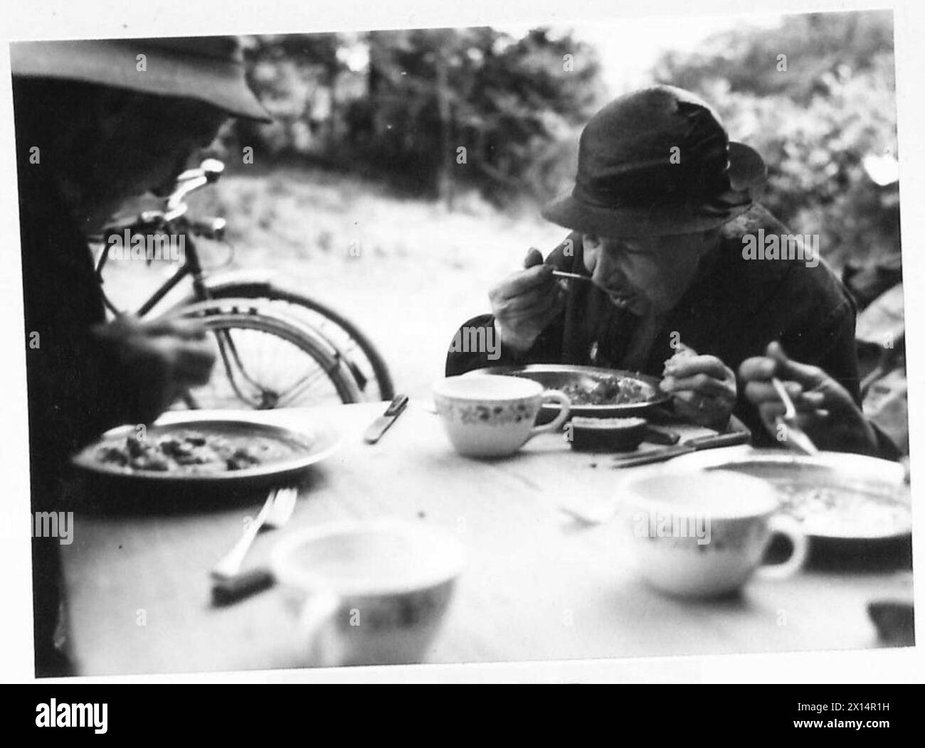 Die Flüchtlinge erhielten ihre erste umfangreiche Mahlzeit seit Tagen, während sie unter der Aufsicht der britischen Armee, 21st Army Group, nach dem Druck einer kostenlosen Zeitung, standen. Stockfoto