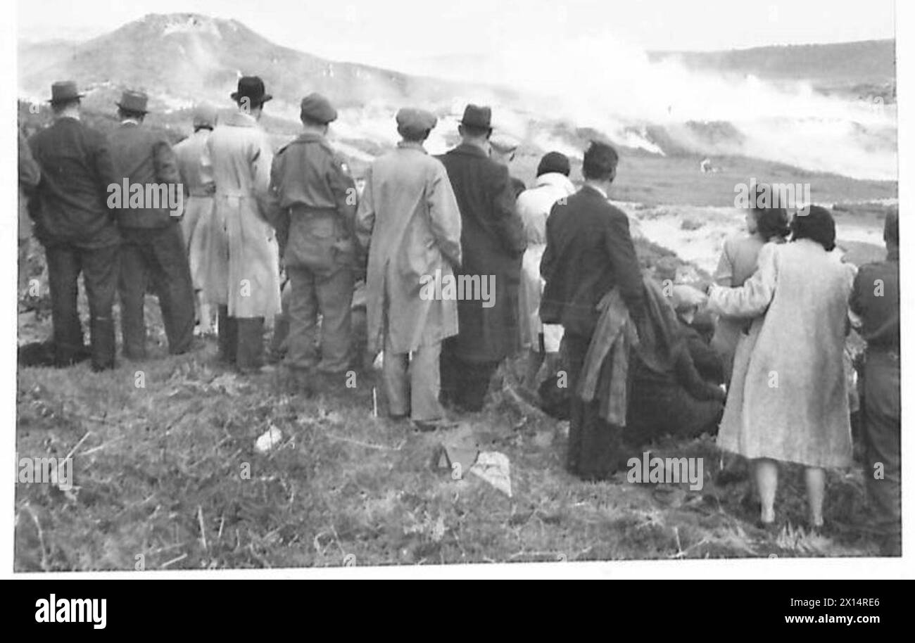Arbeiter beobachten Artillerie, zu der sie beigetragen haben, während während einer militärischen Angriffsdemonstration ein Rauchgitter eingesetzt wird, das die Koordination und den Einsatz von Ausrüstung veranschaulicht. Stockfoto