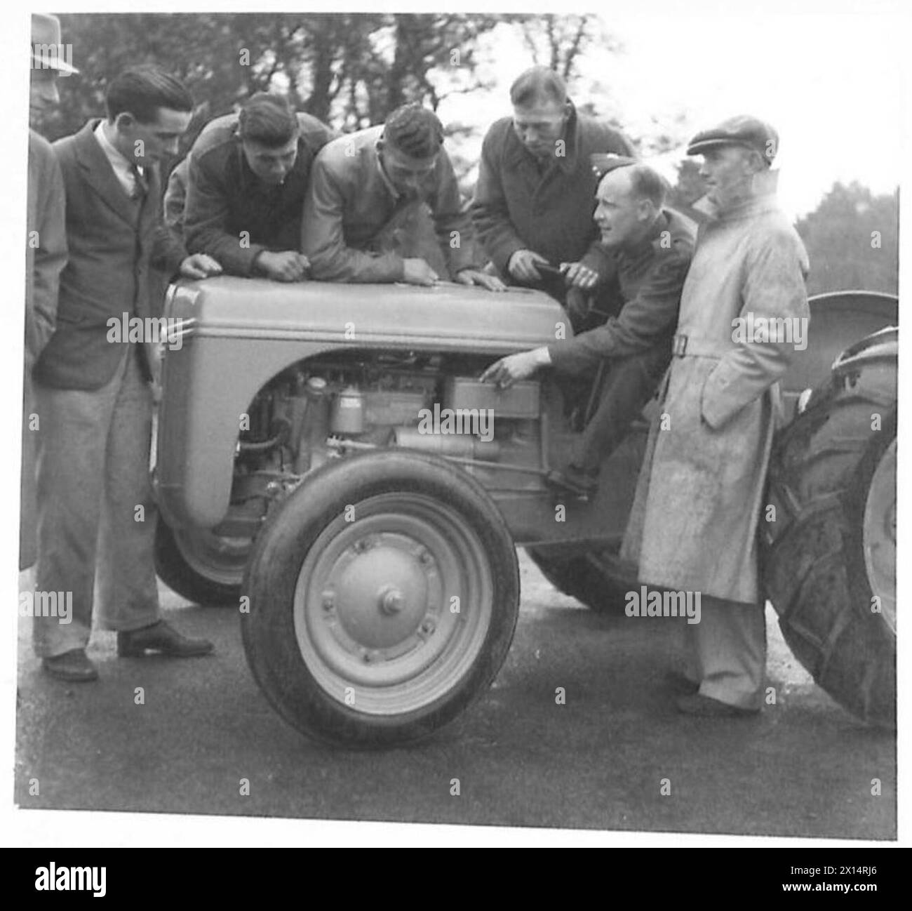 Soldaten geben Junglandwirten im Rahmen praktischer Trainingsübungen Anweisungen zur Traktorwartung, die von einem leitenden NCO gehalten werden. Stockfoto
