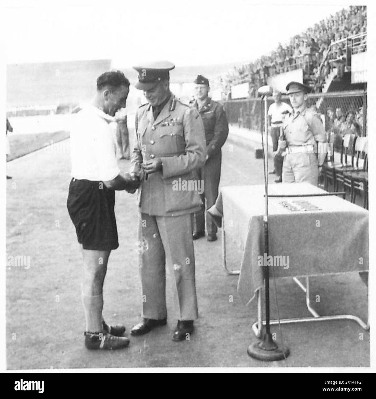 DER ALLIIERTE FUSSBALLMEISTER, der Kapitän des No.3 District Teams, B. Craig (links hinten), wird von General Clows, Commander No.3 District British Army, mit einer Armbanduhr präsentiert Stockfoto