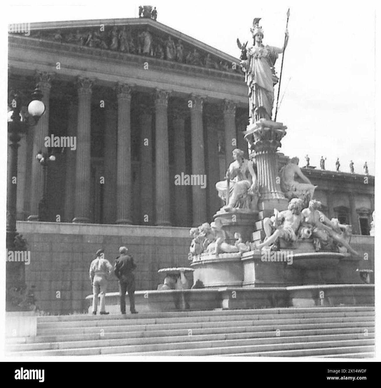 WIEN : VERSCHIEDENE - zwei britische Soldaten untersuchen die Statue, die vor dem Hauptsitz der Wiener NSDAP steht. Dieses Gebäude war eines der wenigen, die die Bombardierung und Beschuss der britischen Armee überlebten Stockfoto