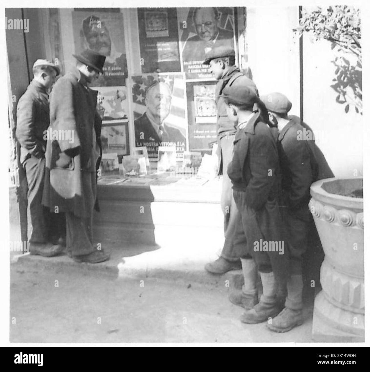 Italienische Bürger beobachten Propagandabilder der Alliierten, die während Operationen der britischen Armee in mehreren europäischen Theatern in einem Fenster gezeigt werden. Stockfoto