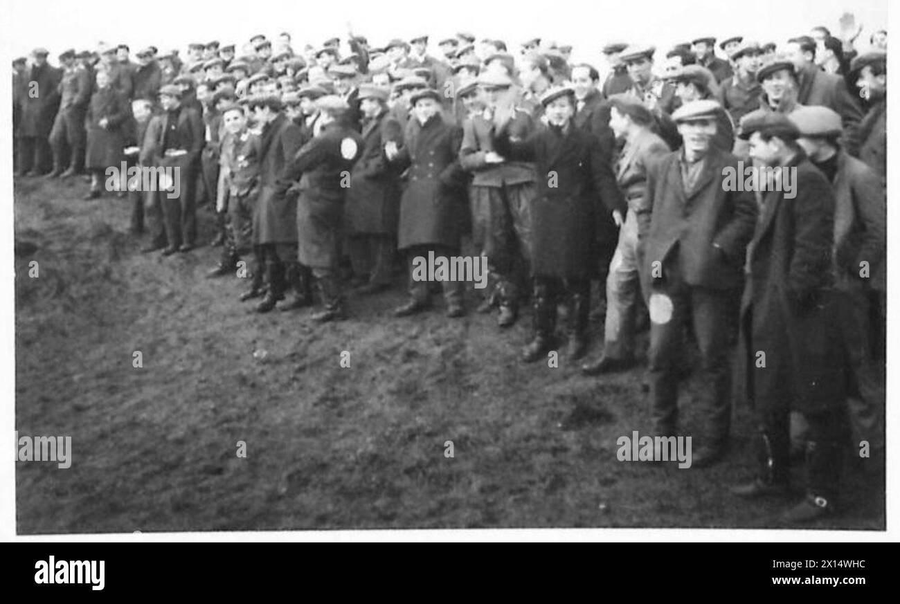 Deutsche Kriegsgefangene werden im Lager gezeigt, um ein Fußballspiel zu beobachten, was die Freizeit und das tägliche Leben in einer Kriegsgefangeneneinrichtung veranschaulicht. Stockfoto