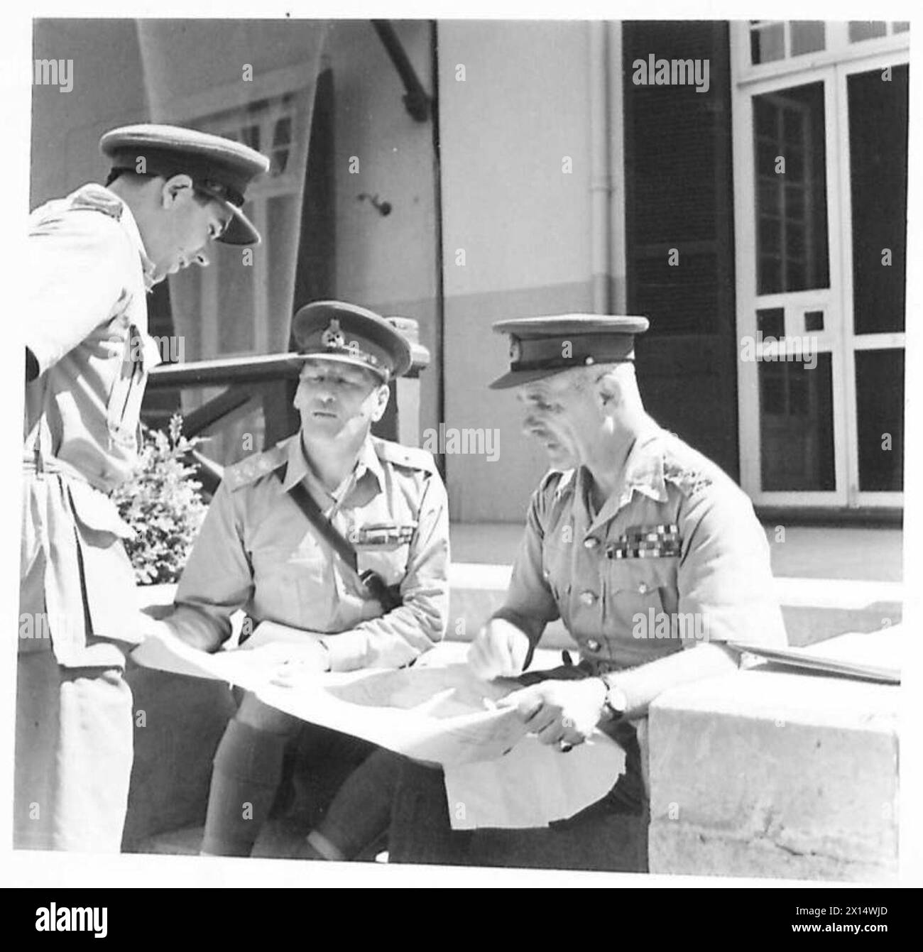 Zwei hochrangige Kriegschefs treffen sich, während ein Kriegsberichterstatter Fragen während eines offiziellen militärischen Ereignisses stellt. Stockfoto