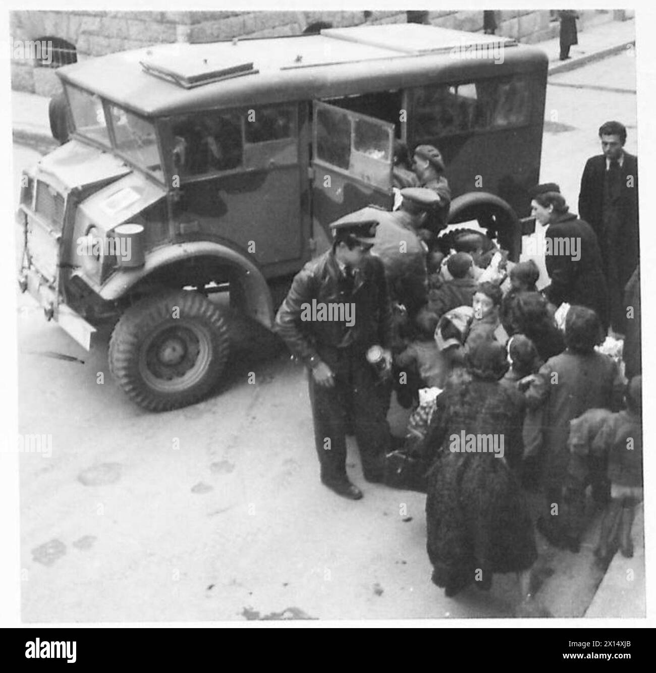 Mitglieder des Mess Shepherd griechische Kinder zu Militärfahrzeugen, die sie während einer Neujahrsfeier nach Hause transportieren. Stockfoto