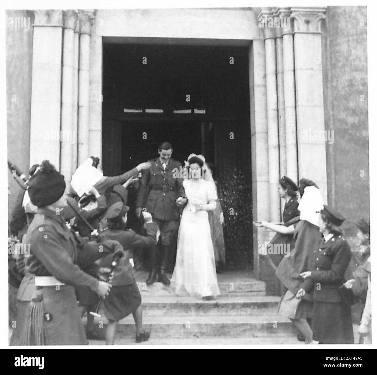 Die Braut und der Bräutigam verlassen die Kirche nach ihrer Trauung am St. Patrick's Day, wobei Militärpersonal anwesend ist. Stockfoto