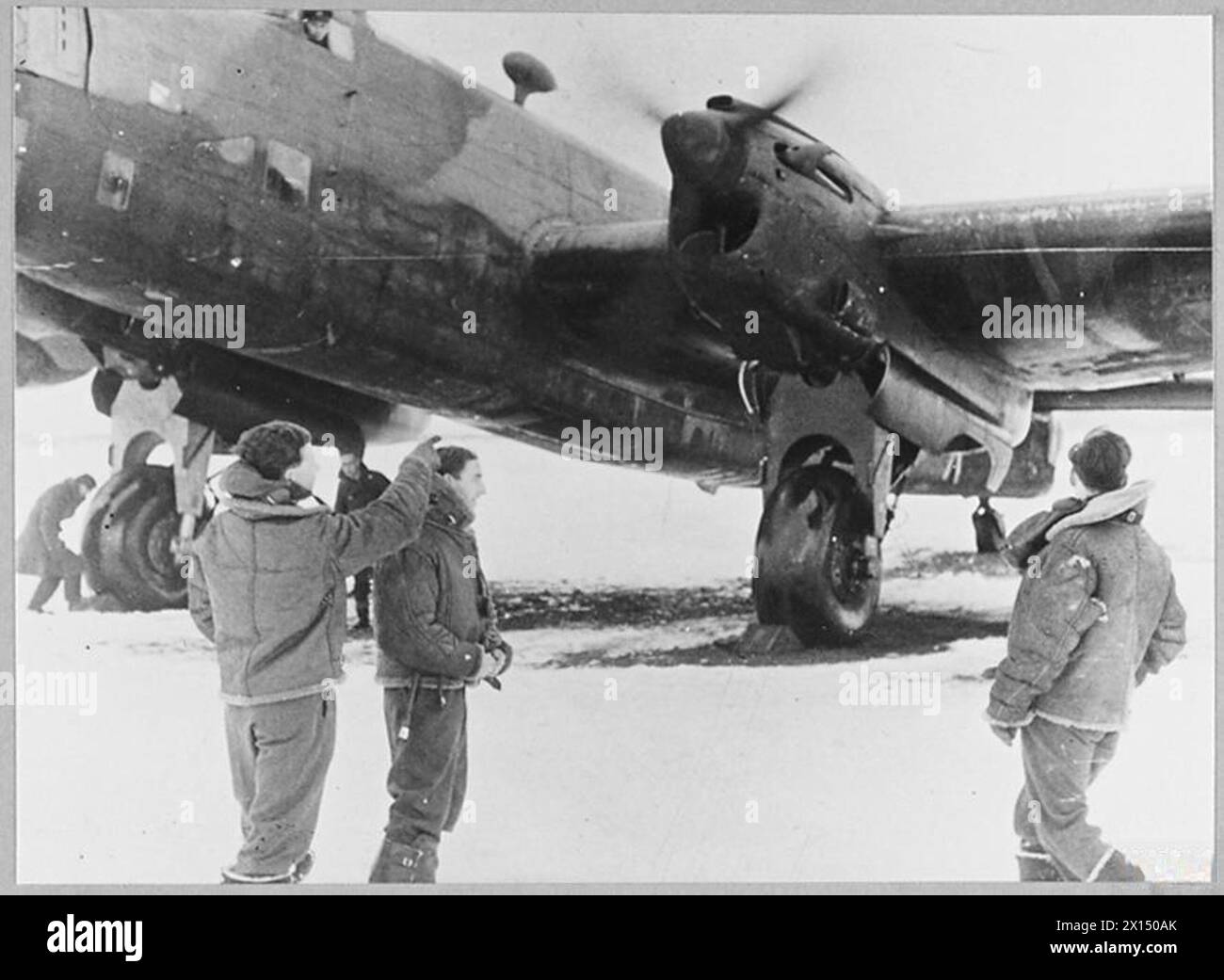 Mitglieder der No. 35 Squadron, RAF, Paddy, Martin und Henry, warten Sie bei schneebedeckten Bedingungen, während ihre Halifax Bomberantriebe 1941 aufgewärmt werden. Stockfoto