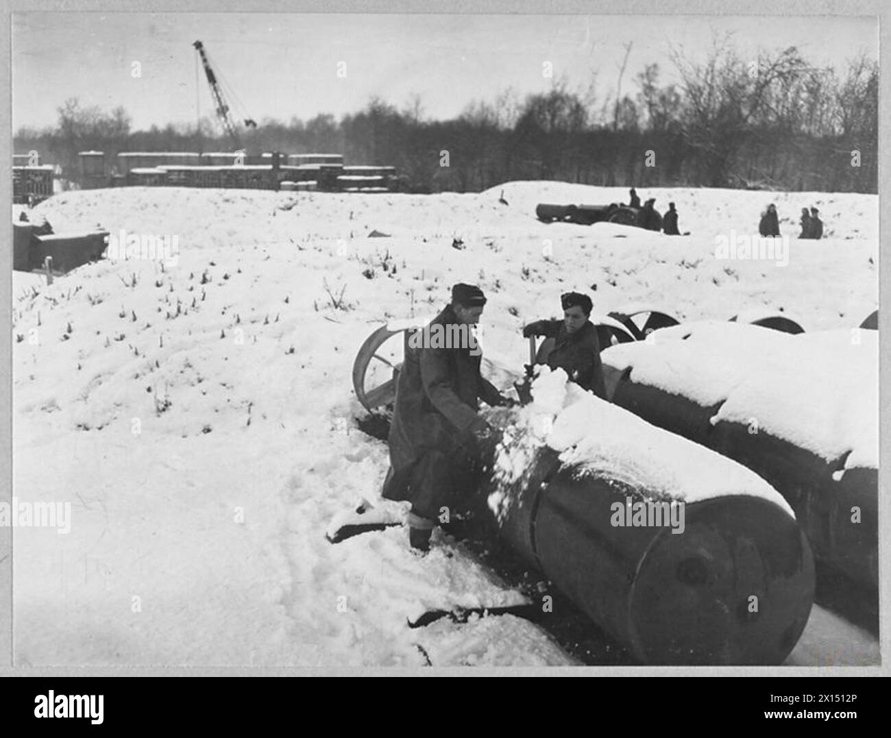RAF-Flieger räumen Landebahnen und enteisen schwere Bomber auf einem Bomberflugplatz in Großbritannien während des Schneefalls, um die Operationen des Bomber Command gegen deutsche Ziele aufrechtzuerhalten, während Kadetten bei der Vorbereitung helfen. Stockfoto