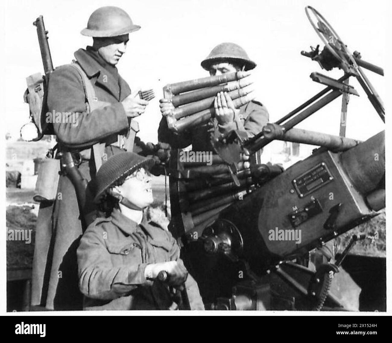 Pte. Johnson vergleicht seine Munitionsclips mit denen, die von der Besatzung einer Flugabwehrkanone am Anzio-Brückenkopf verwendet wurden. Stockfoto
