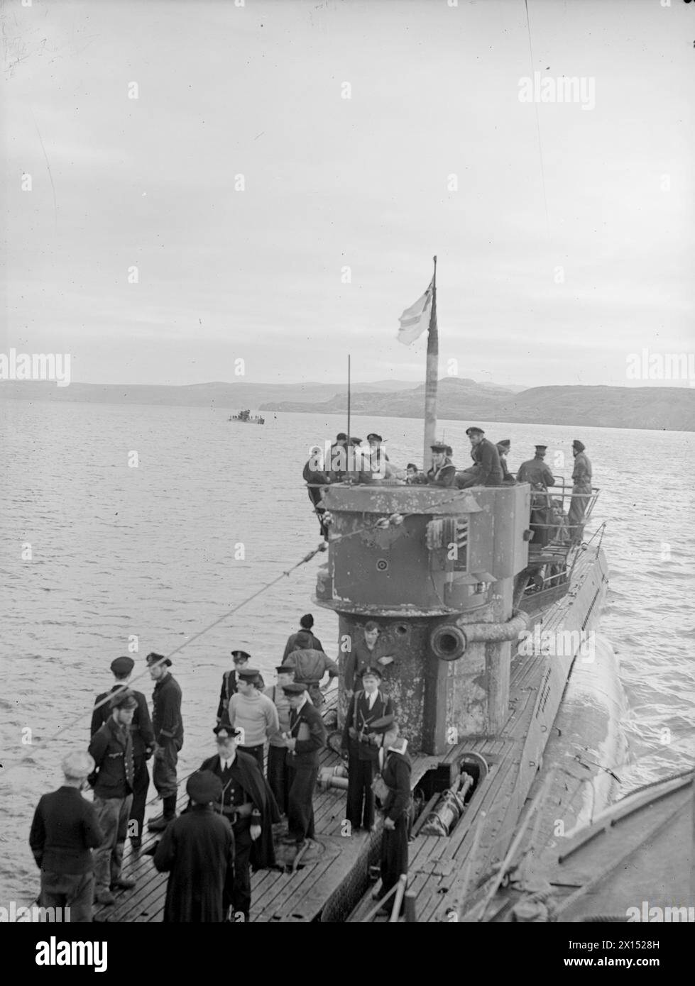 U-BOOTE ERGEBEN SICH AM LOCH ERIBOLL. 9. UND 10. MAI 1945, LOCH ERIBOLL, SCHOTTLAND. DIE ERSTE DEUTSCHE U-BOOT-FLOTTE BEGANN IHRE KAPITULATION VOR DEN TRUPPEN DER ROYAL NAVY. - Die White Fähnrich fliegt über U 826, als sie zum Loch kommt, um sich zu ergeben, gefolgt von U 236 im Hintergrund. Beachten Sie die britische Marinewache unter der deutschen Besatzung Stockfoto