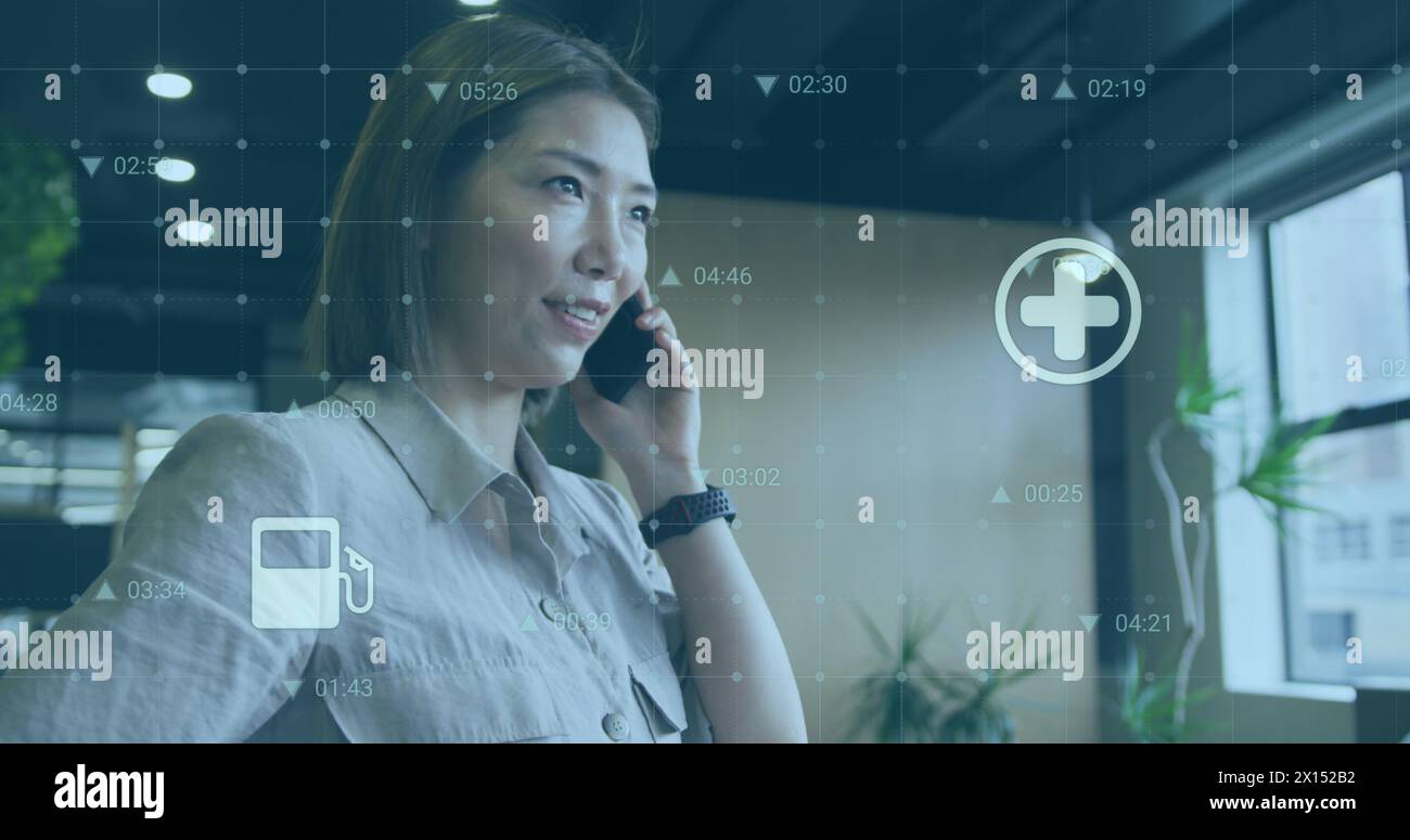 Bild von wechselnden Zahlen und mehreren Symbolen über asiatische Frau, die auf dem Handy steht und spricht Stockfoto