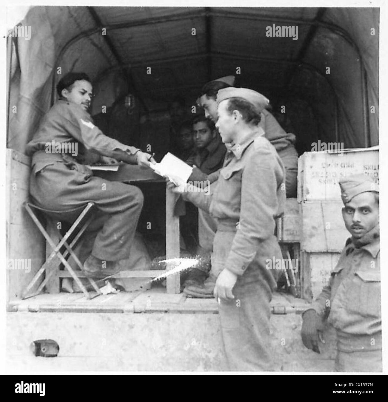 Der private G. Pope vom Recce Regiment verteilt Rationsscheine an indische Havildar Sergeants des Royal Indian Army Service Corps, achte Armee in Italien. Stockfoto
