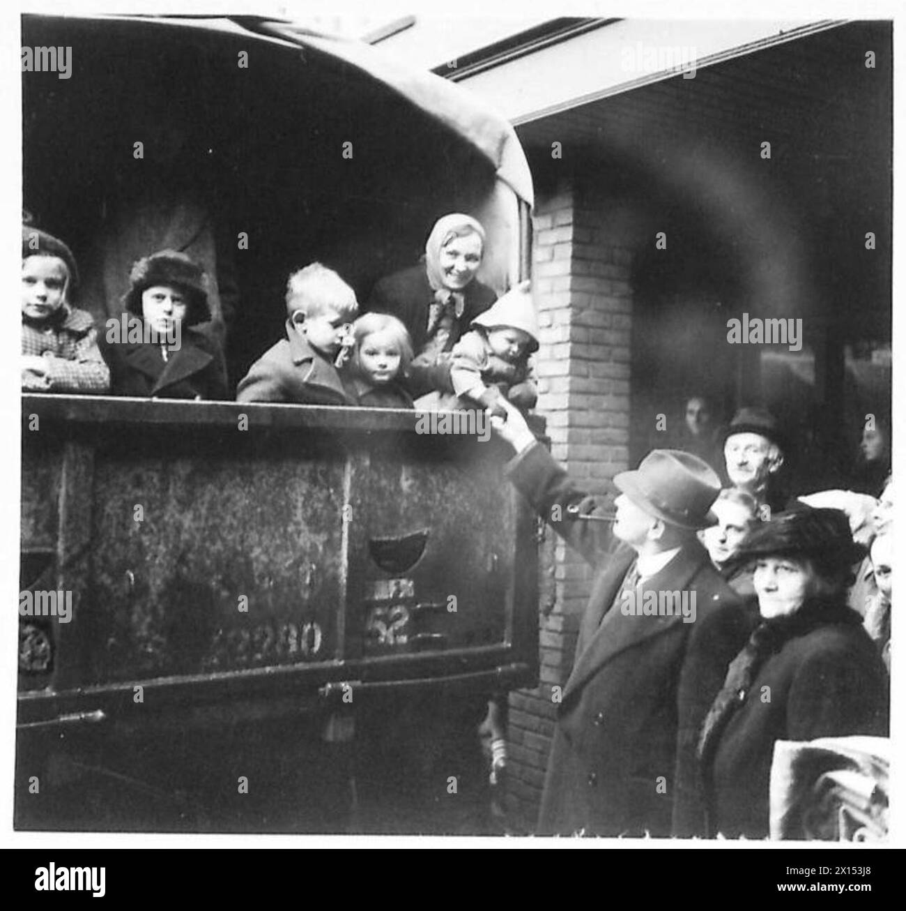 Flüchtlinge aus Blerick ziehen in einem Militärwagen in neue Häuser, begrüßt von Mr. Cox, einem Zeitungsdirektor, nachdem britische Truppen eingetroffen waren. Stockfoto