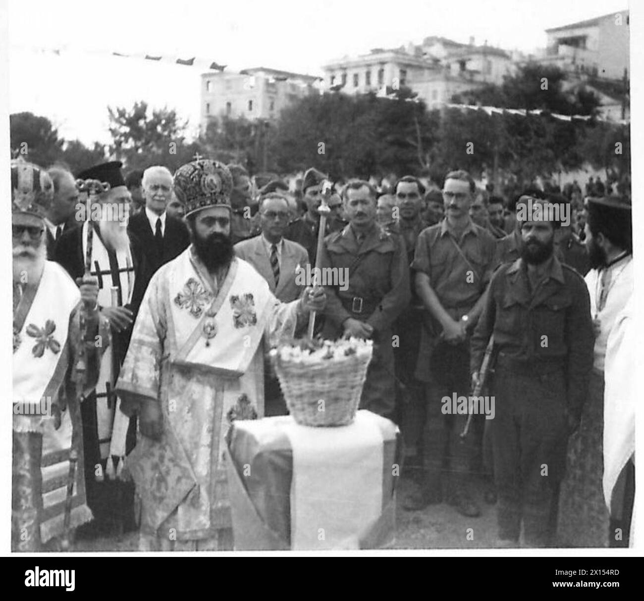 Zwei Bischöfe stehen an einem improvisierten Cenotaph, während General Kamaras und Herr Makus im Hintergrund anwesend sind. Stockfoto
