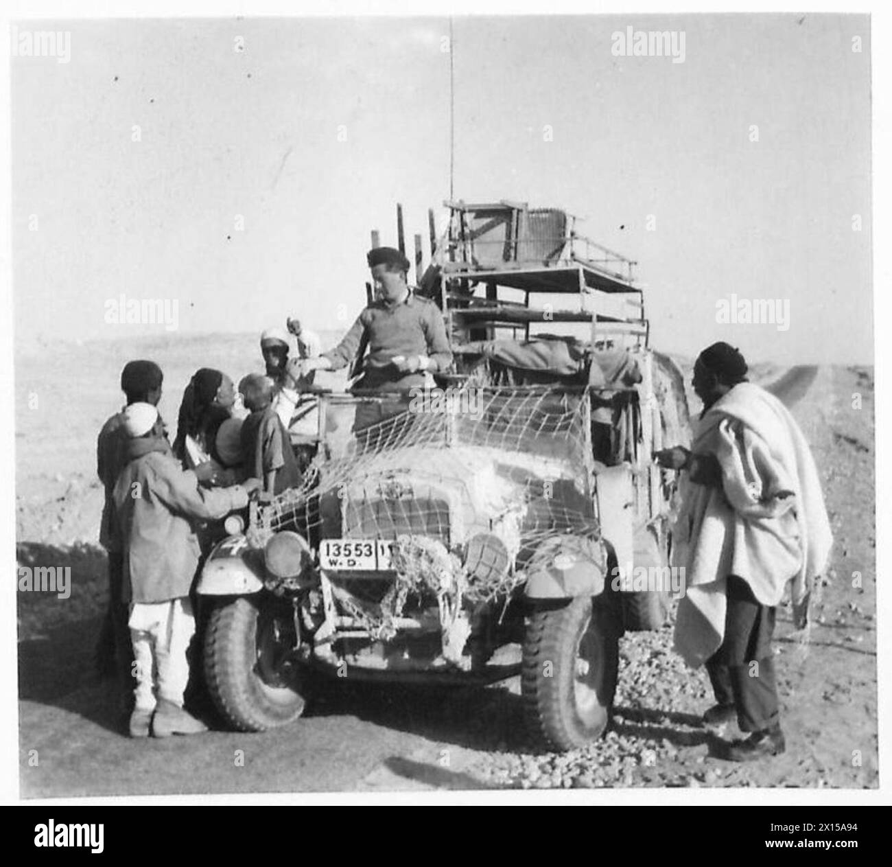Britische Offiziere rücken entlang der Tobruk-Derna-Straße in der Westwüste vor und interagieren mit befreundeten Beduinen, die Informationen zur britischen Armee liefern. Stockfoto Britische Offiziere rücken entlang der Tobruk-Derna-Straße in der Westwüste vor und interagieren mit befreundeten Beduinen, die Informationen zur britischen Armee liefern. Stockfoto