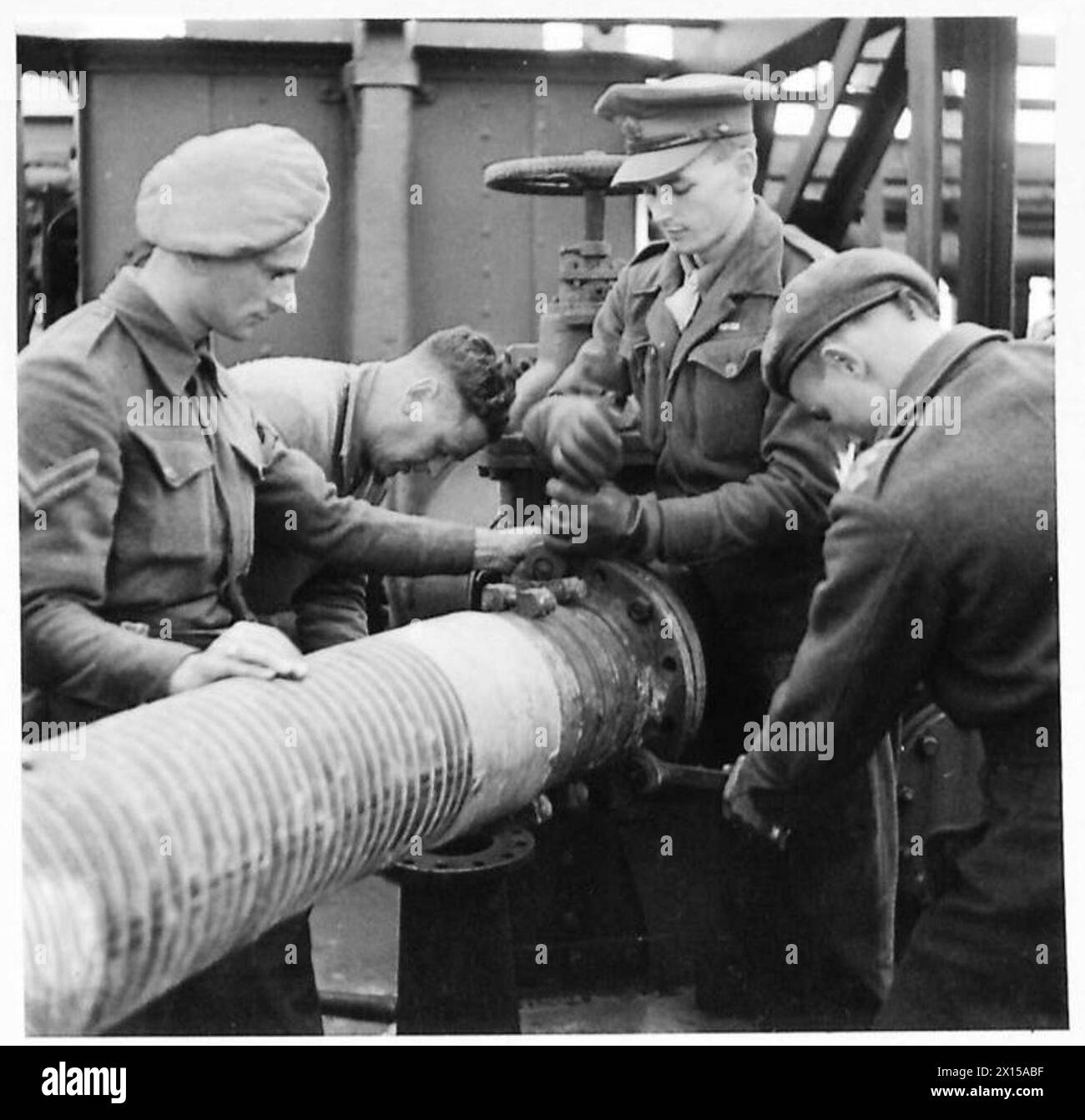 RASC-Mitarbeiter und italienische Pioniere positionieren einen 18-Zoll-Schlauch an Bord der „Empire Emerald“ in Ancona Docks, der logistische Operationen und die Handhabung der Ausrüstung für die achte Armee demonstriert. Stockfoto