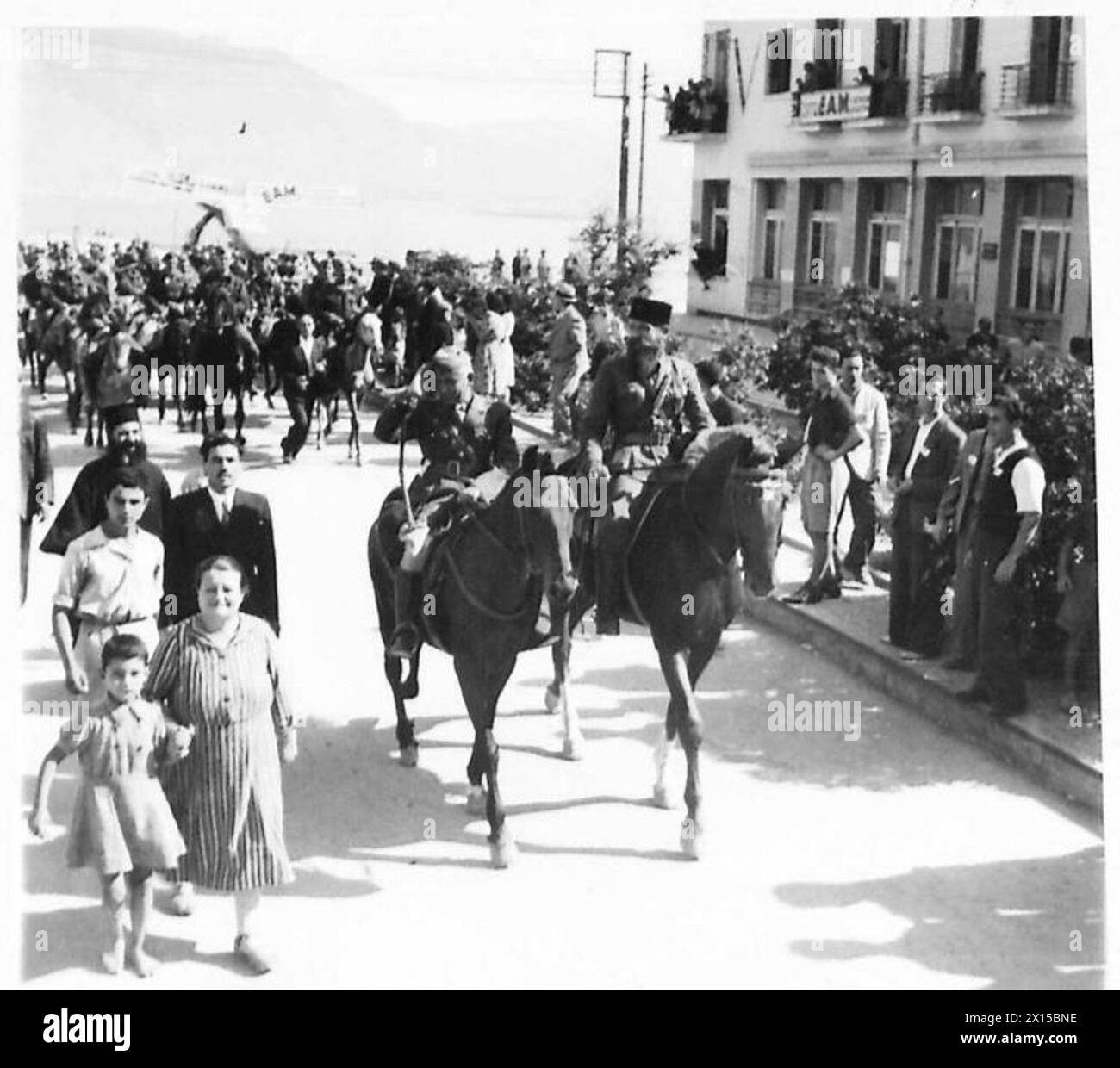 Britische Truppen betreten Korinth, als ein Brigadier der E.L.A.S. in einer Straßenprozession zu Pferd reitet. Stockfoto
