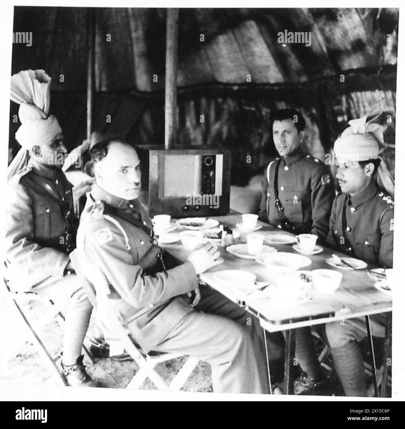 Indische Offiziere des Royal Indian Army Service Corps trinken zusammen Tee in einem Zelt, das von der britischen Armee benutzt wird. Stockfoto