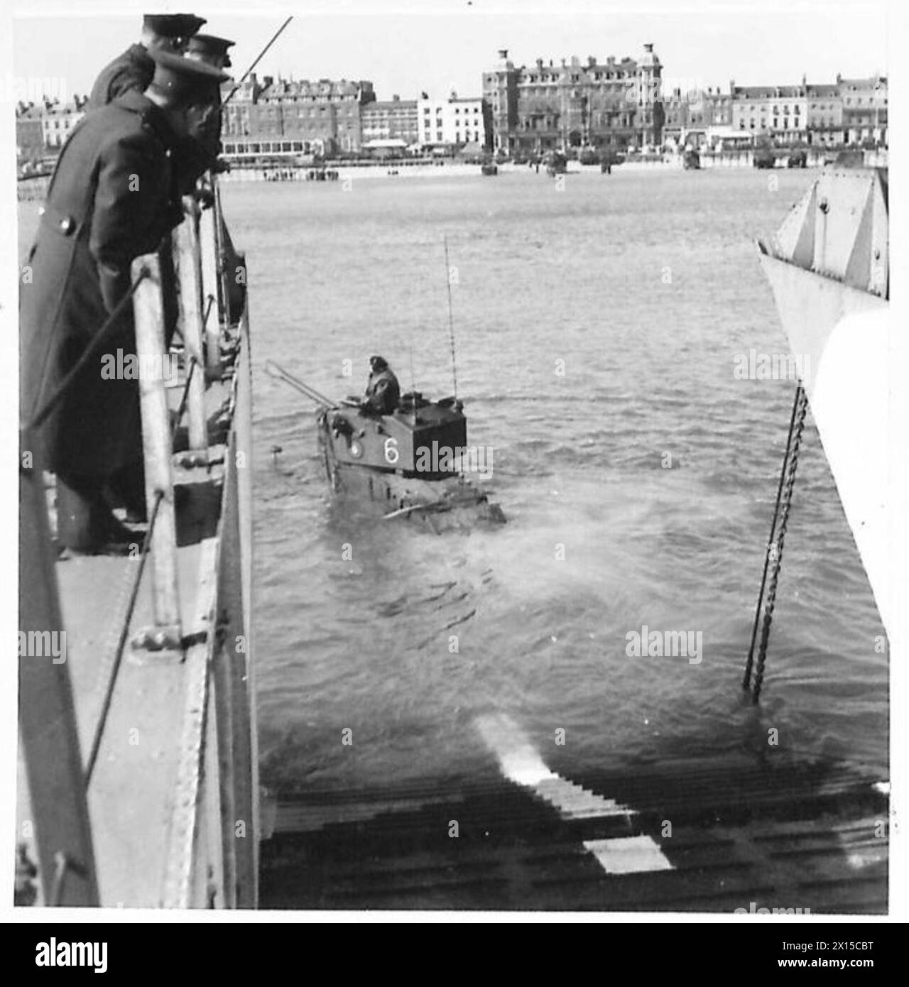 Gepanzerte Autos A.E.C. steigen von einem Landing Craft Tank in vier Fuß Wasser aus, bleiben kurz bevor sie an Land gelangen und demonstrieren die Fähigkeiten amphibischer Fahrzeuge. Stockfoto