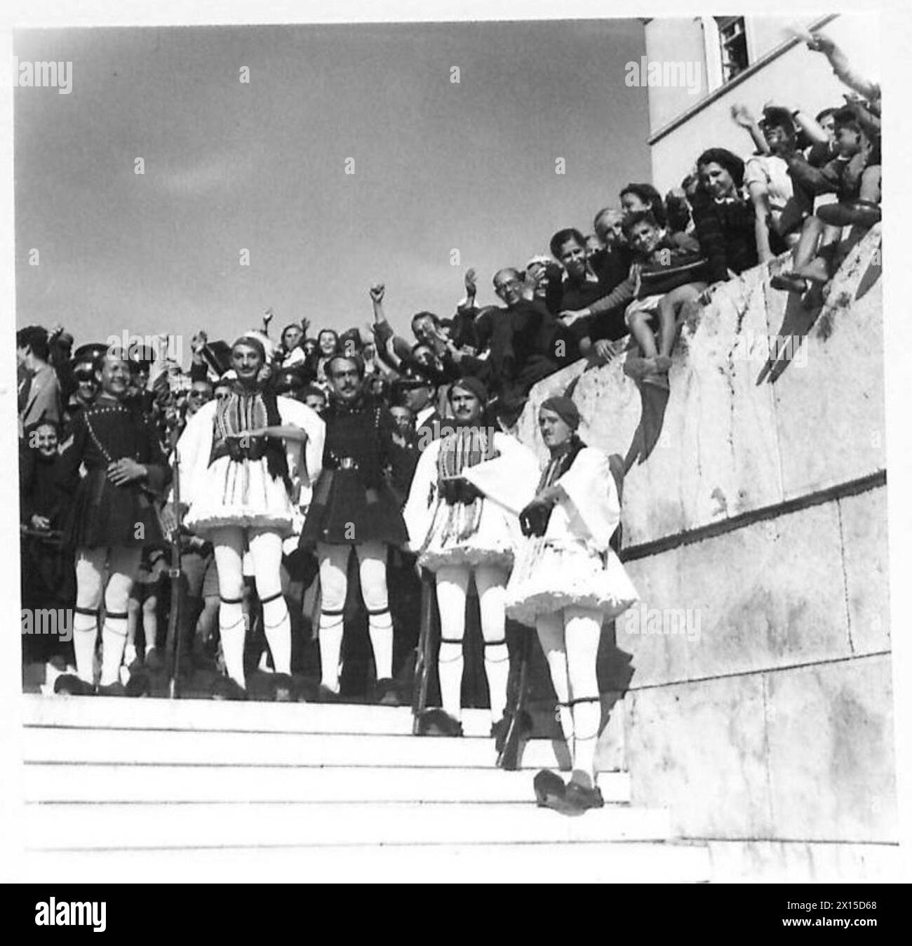 DIE BRITISCHE ARMEE IN NORDAFRIKA, SIZILIEN, ITALIEN, DEM BALKAN UND ÖSTERREICH 1942-1946 - eine Auswahl nationaler Kostüme unter den Menschen, die auf den Premierminister der britischen Armee warten Stockfoto