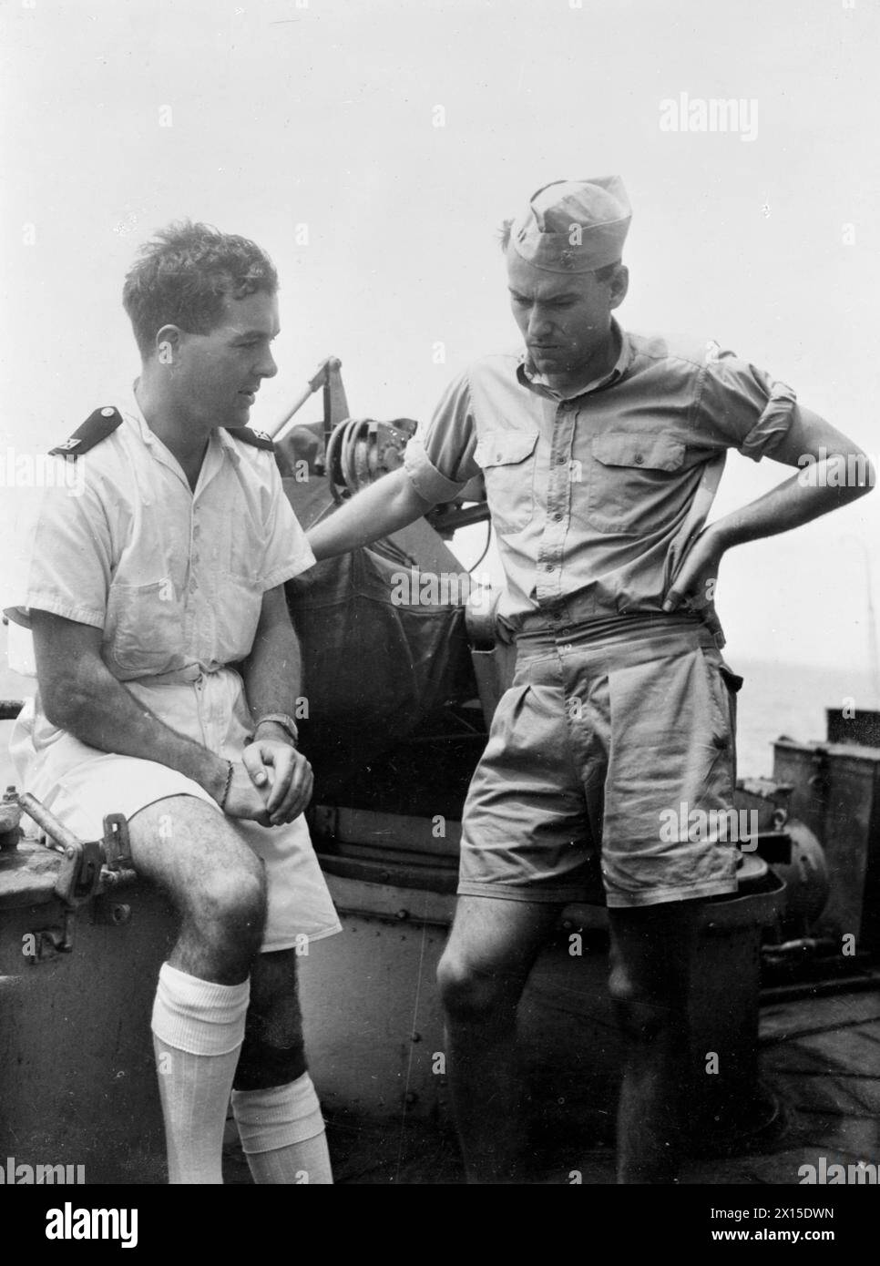 Im August 1945 spricht der Kaplan Rev J Trainer an Bord der HMS Formidable im Dienst der Pazifikflotte mit dem US Navy Liaison Officer Lt W E Rayne auf der Fo’c’sle. Stockfoto