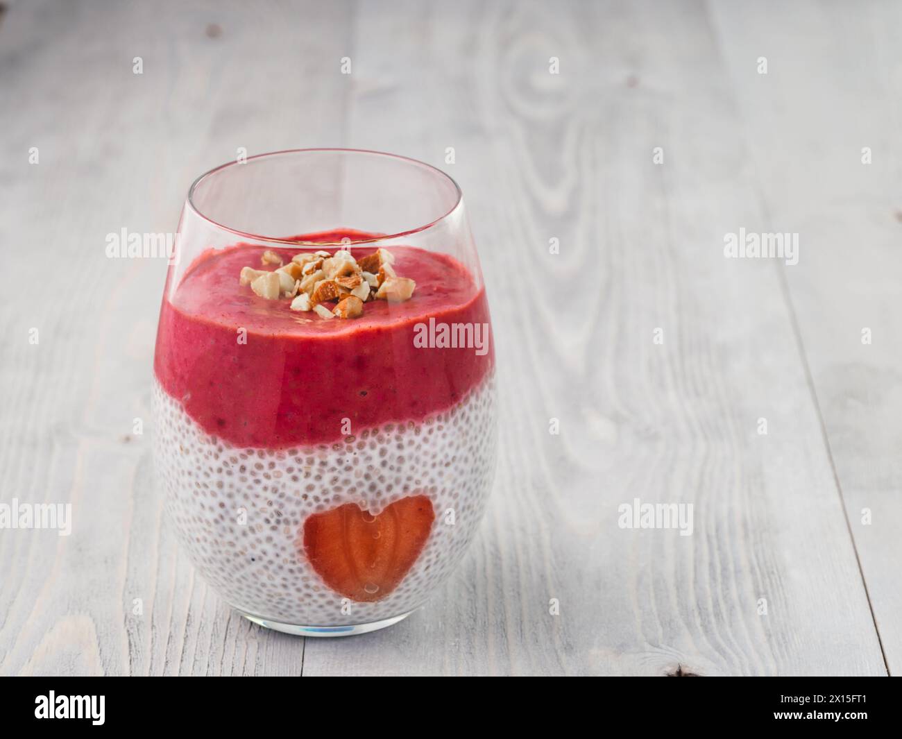Idee für gesundes Frühstück am Valentinstag: Chia Pudding mit roten Beeren Püree, gehackte Mandeln auf und Erdbeere in der Form des Herzens. Kopieren Sie Platz für Text Stockfoto