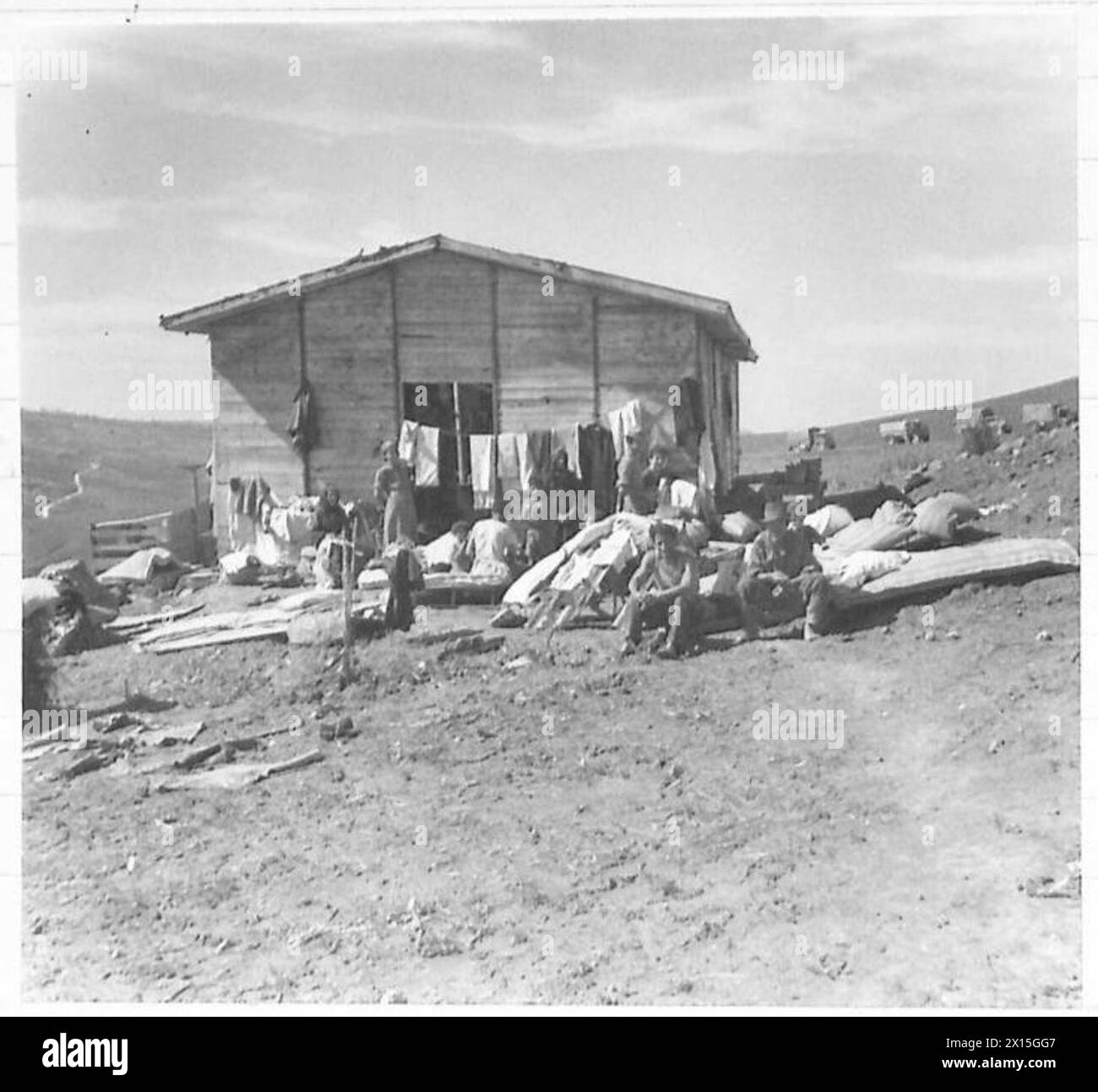 8. ARMEE: VERSCHIEDENE italienische Familien, die durch den Beschuss obdachlos geworden sind, finden Zuflucht in einer Holzhütte der britischen Armee Stockfoto