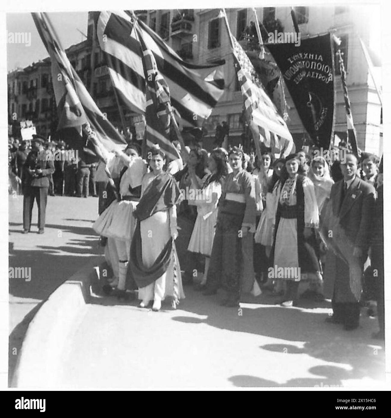 Frauen in Nationalkleidung tragen Banner, während sie die Rede des Erzbischofs während des Besuchs des griechischen Regenten in Salonika, der britischen Armee, hören. Stockfoto Frauen in Nationalkleidung tragen Banner, während sie die Rede des Erzbischofs während des Besuchs des griechischen Regenten in Salonika, der britischen Armee, hören. Stockfoto
