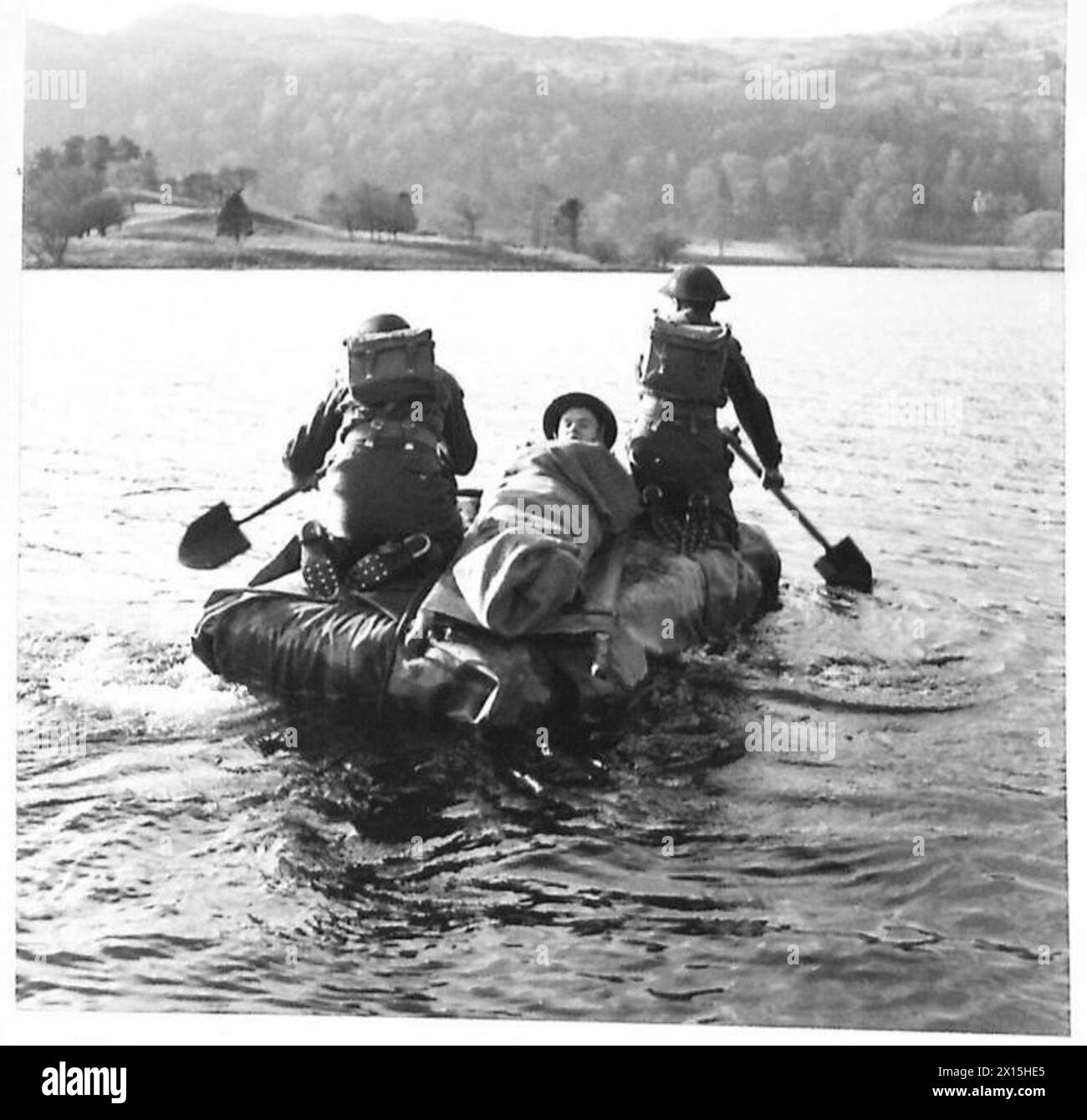 Eine FELDAMBULANZEINHEIT IM KAMPFTRAINING - zwei medizinische Pfleger nehmen einen „Unfall“ über einen See auf einem improvisierten Schiff. Sie besteht aus drei Strohballen, die mit einem Leinwandtuch umwickelt sind. Pik wird verwendet, um das improvisierte Floß British Army zu paddeln Stockfoto
