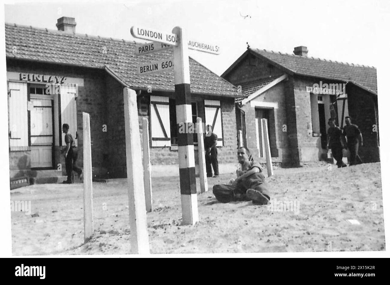 Zeigt das 8. Corps Rest Camp mit Finlays NAAFI Shop, Friseurladen und Wegweisern für London, Paris und Berlin, British Army, 21st Army Group. Stockfoto
