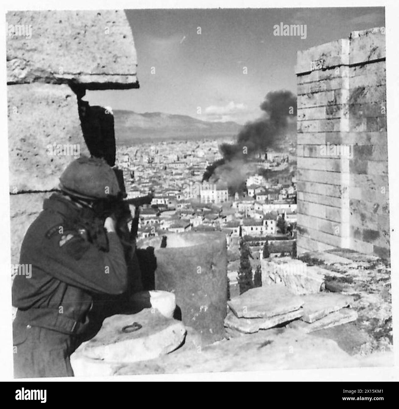 Private L. Blacknell vom 5. Bataillon Scottish Fallschirmregiment ist in Athen stationiert, um E.L.A.S.-Truppen zu erwischen, die ein brennendes Gebäude verlassen, wobei britische Armee die Akropolis besetzt. Stockfoto
