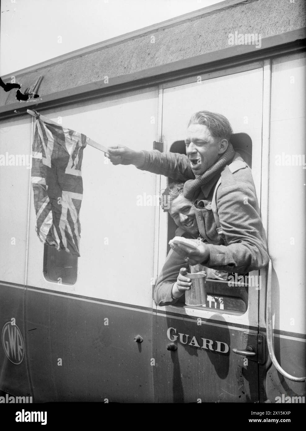 Britische Truppen schwenken am 1. Juni 1940 während der Evakuierung aus Dünkirchen eine Union-Flagge aus einem Zug am Bahnhof Headcorn in Kent, was Erleichterung und Moral nach der Operation zum Ausdruck brachte. Stockfoto