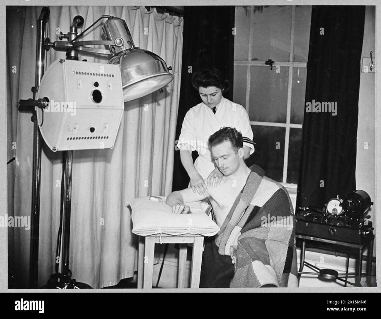 Die W.A.A.F. Masseurin „Snookie“ behandelt die Schulter eines Fliegers in einem großen R.A.F. Krankenhaus im Jahr 1943 und fördert die Erholung und Mobilität. Stockfoto
