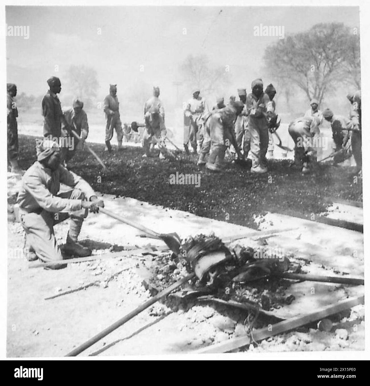 Indische Pioniere der Fünften Armee hacken über Teersteine, während sie Straßen reparieren und Versorgungswege und Transportwege in Einsatzgebieten beibehalten. Stockfoto