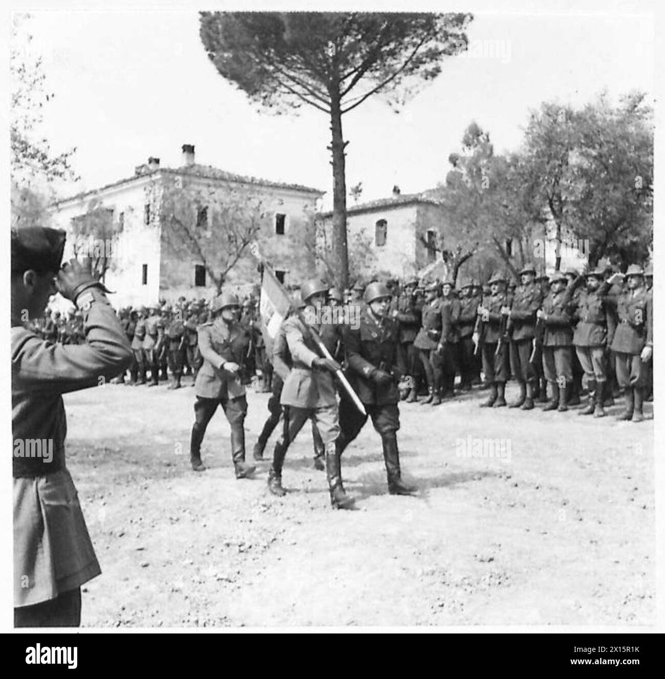 Der italienische Kriegsminister inspiziert das italienische Befreiungskorps, während die Infanterie-Flagge auf einer Parade steht. Stockfoto